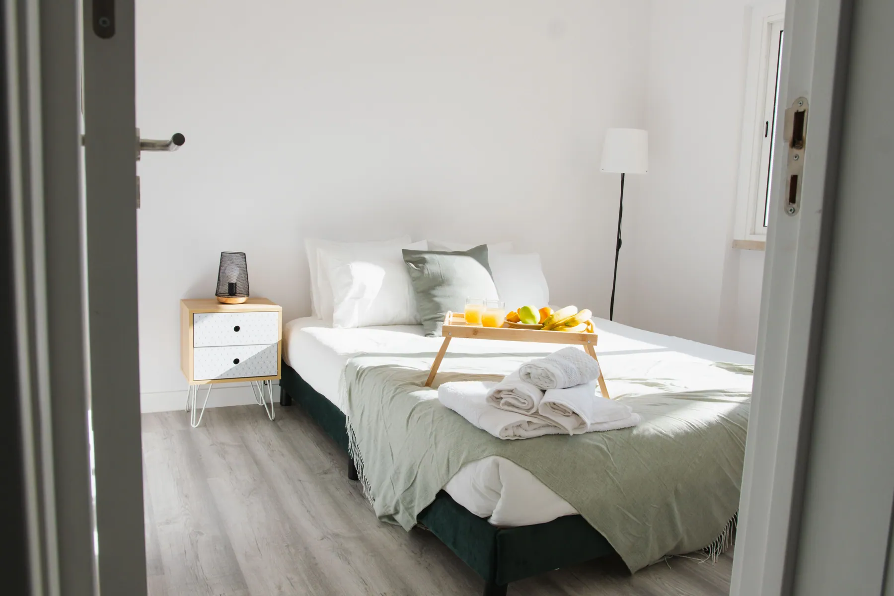 Guest bedroom set with folded towels and a breakfast tray