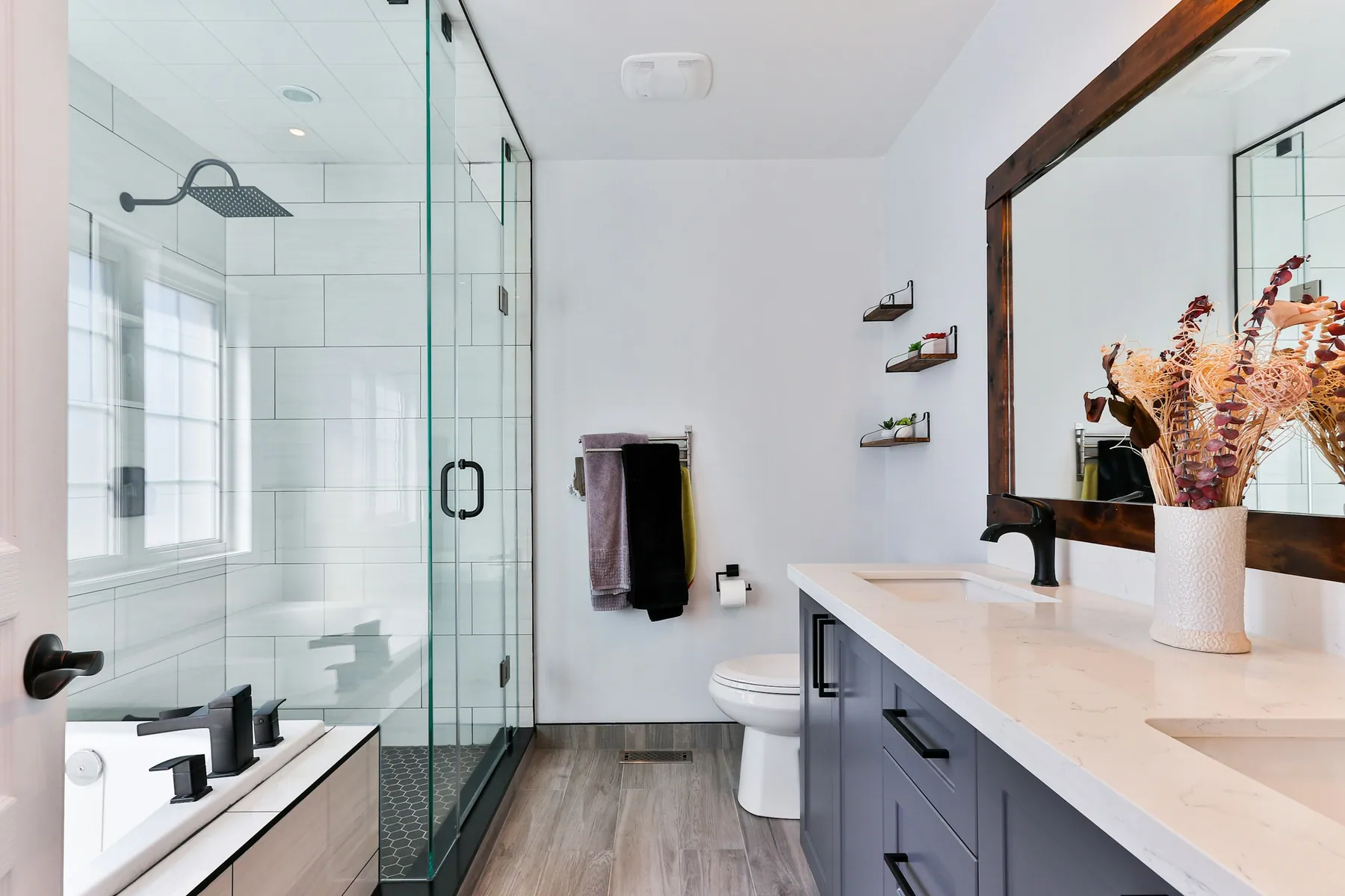 Bright modern bathroom with a frameless glass walk-in shower and a quartz double vanity