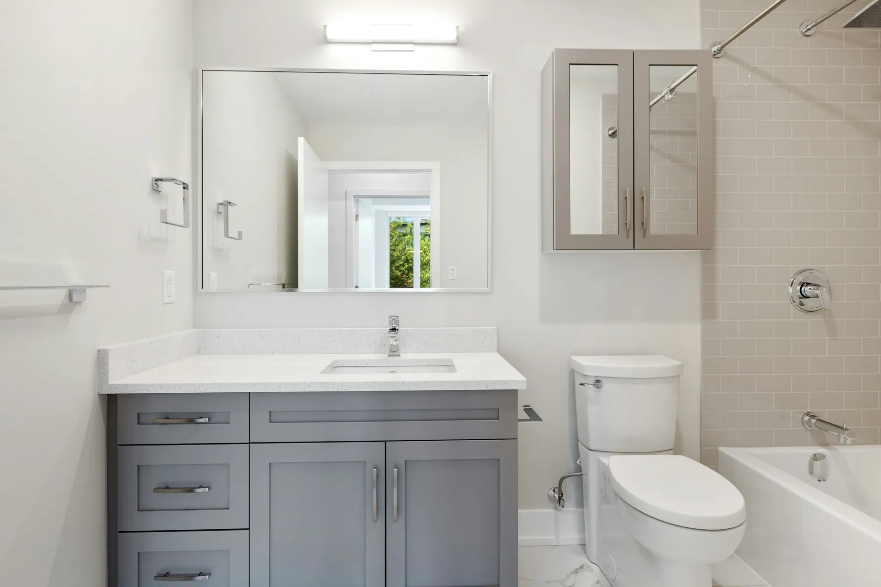 Compact family bathroom with a gray shaker vanity, toilet and tub-shower