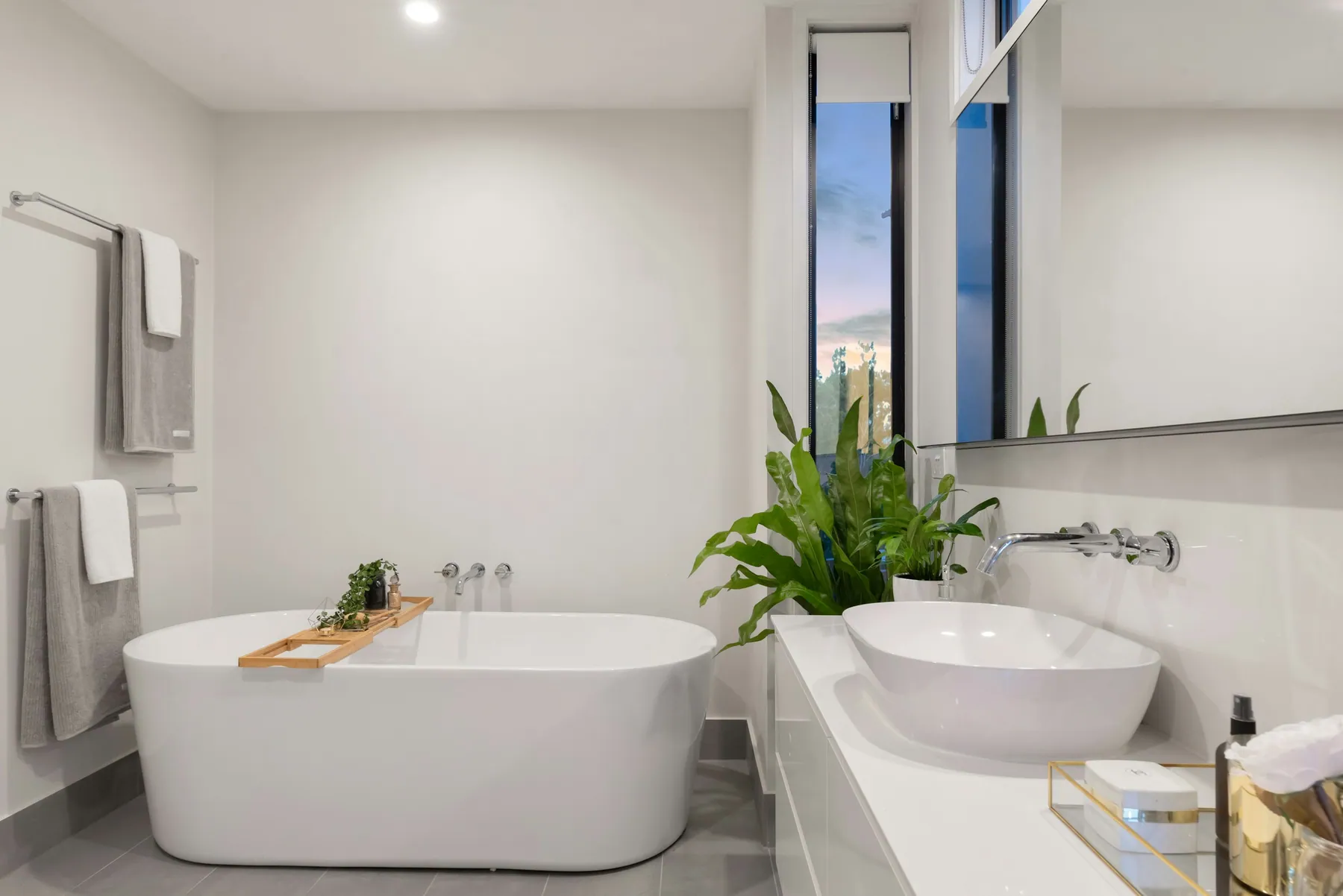 Minimal white bathroom with a freestanding tub, vessel sink and fresh plants