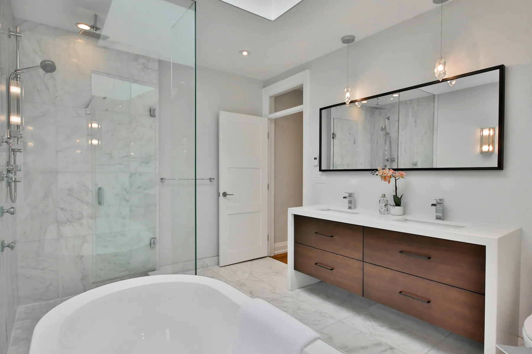 Marble master bath with a glass shower, floating double vanity and soaking tub