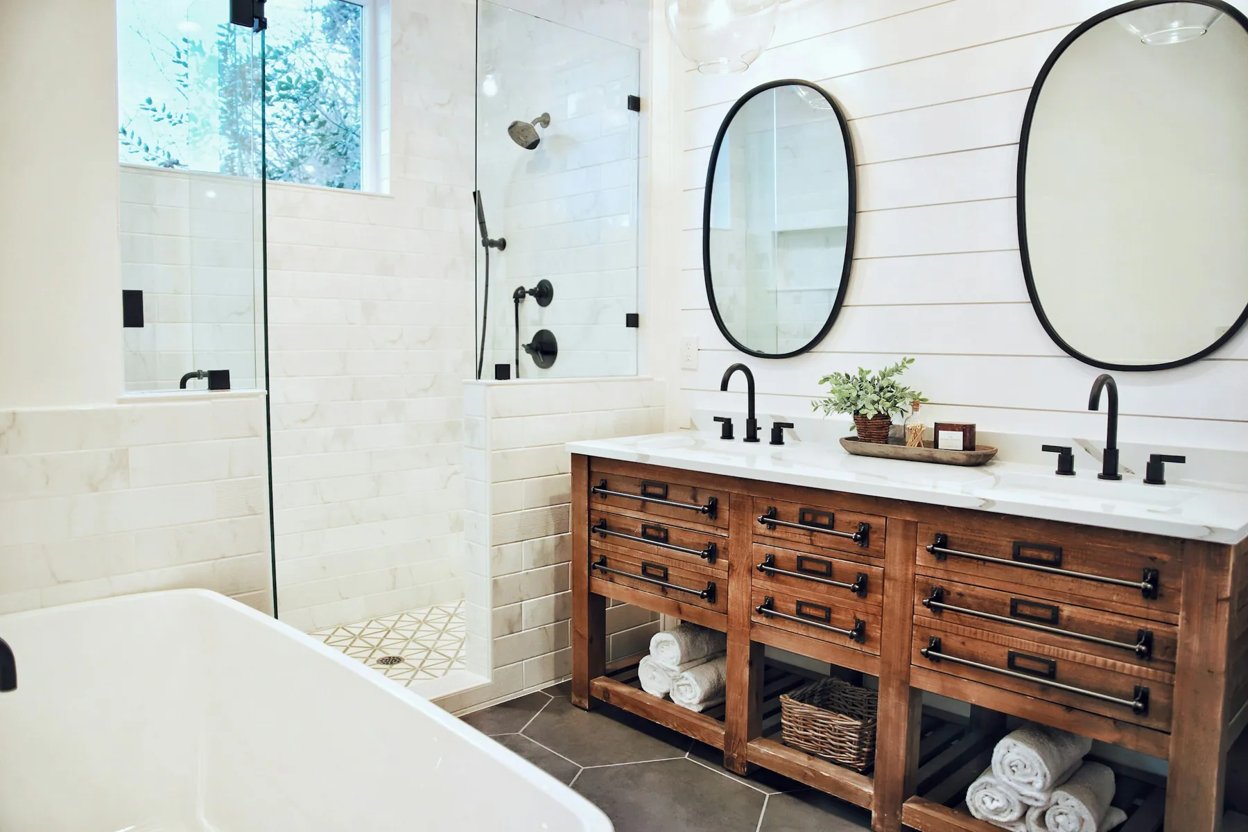 Farmhouse bathroom with shiplap walls, a wood double vanity, glass shower and tub