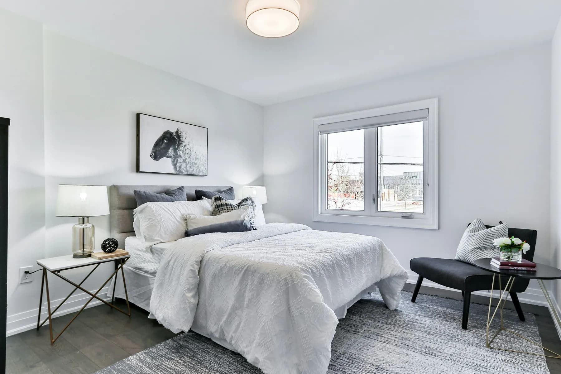 Bright bedroom with a freshly made bed, white bedding and reading chair