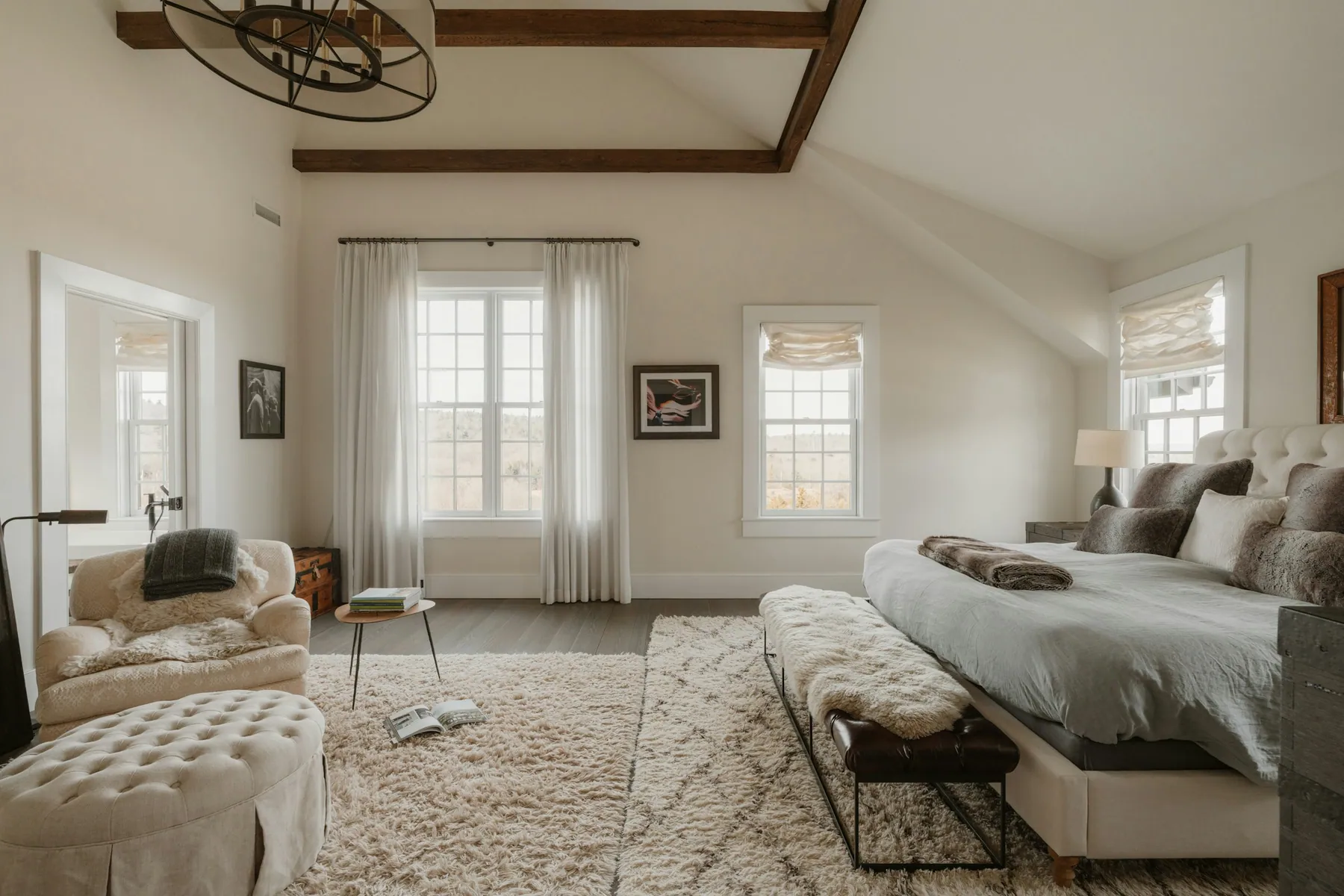 Large beamed bedroom with a sitting area and sheer curtains