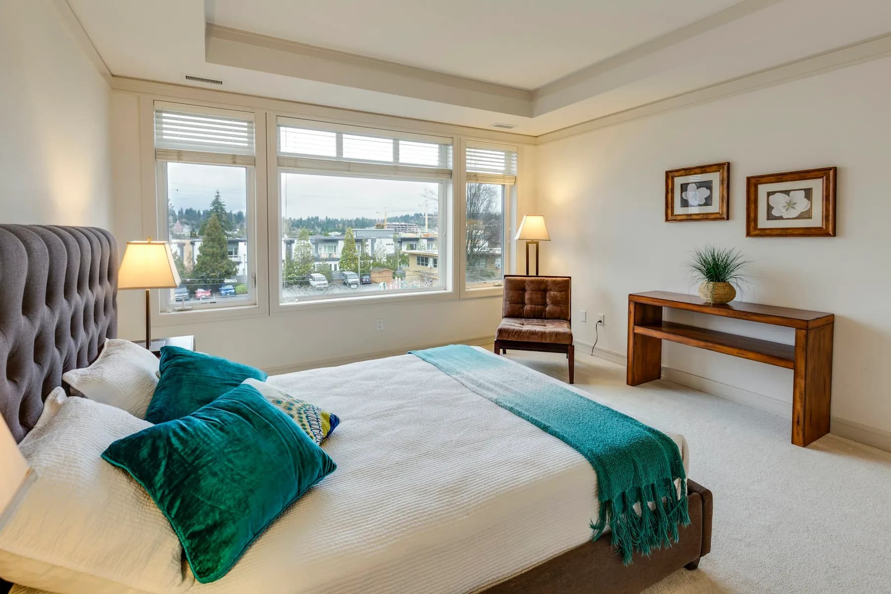 Master bedroom with a tufted headboard, teal throw and picture windows