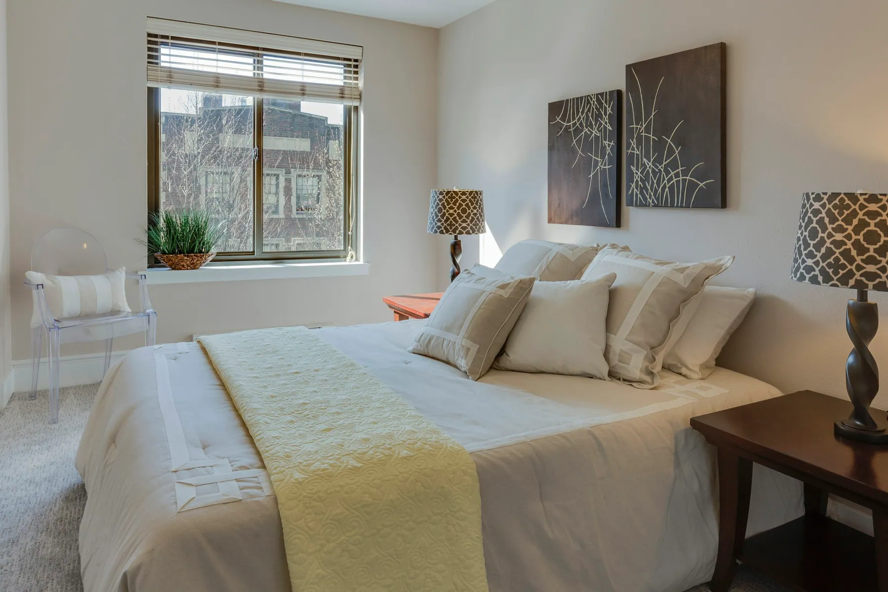 Neatly made bed with layered linens and patterned lamps