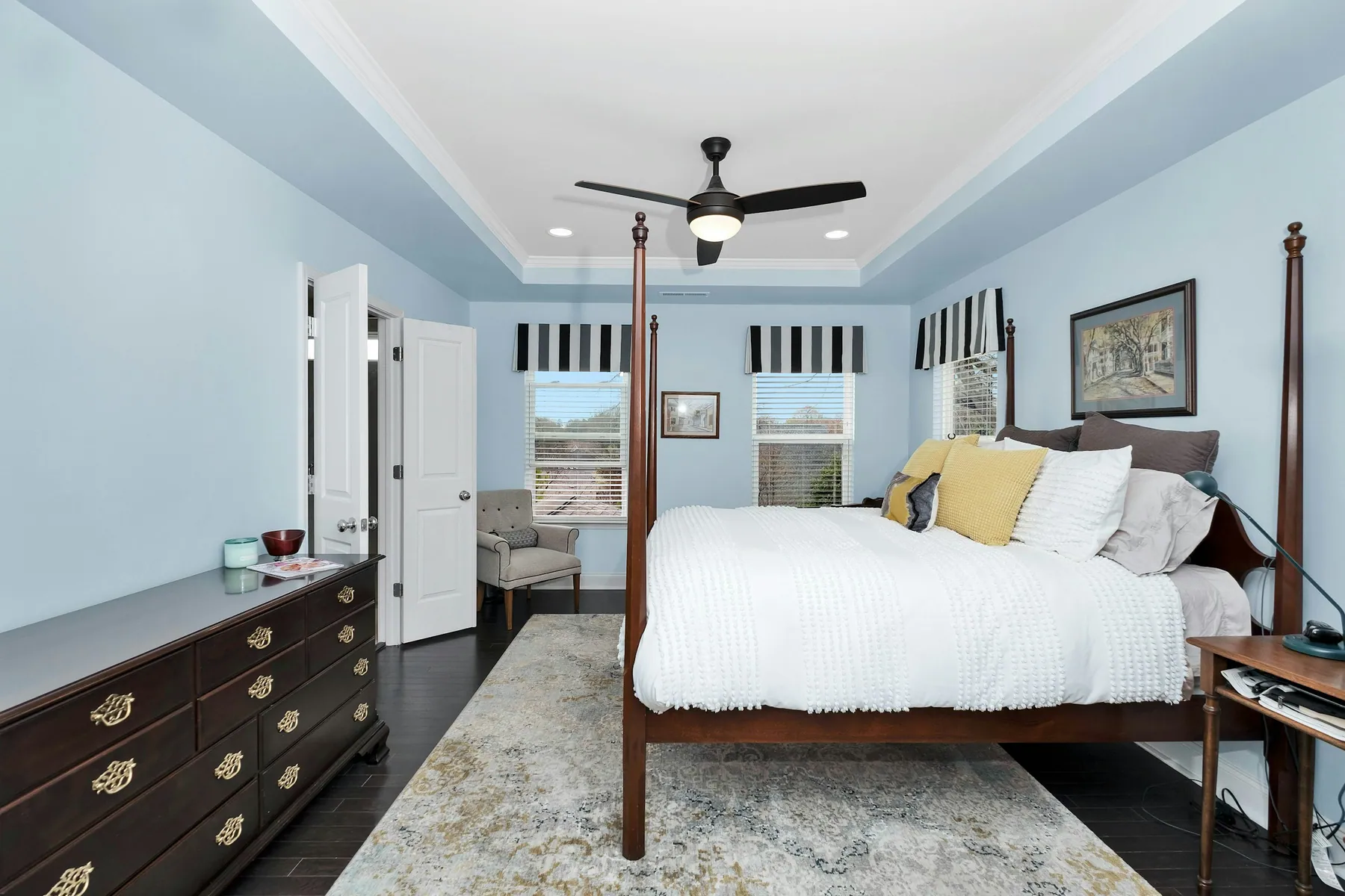 Four-poster bed in a bright blue bedroom with a dark wood dresser