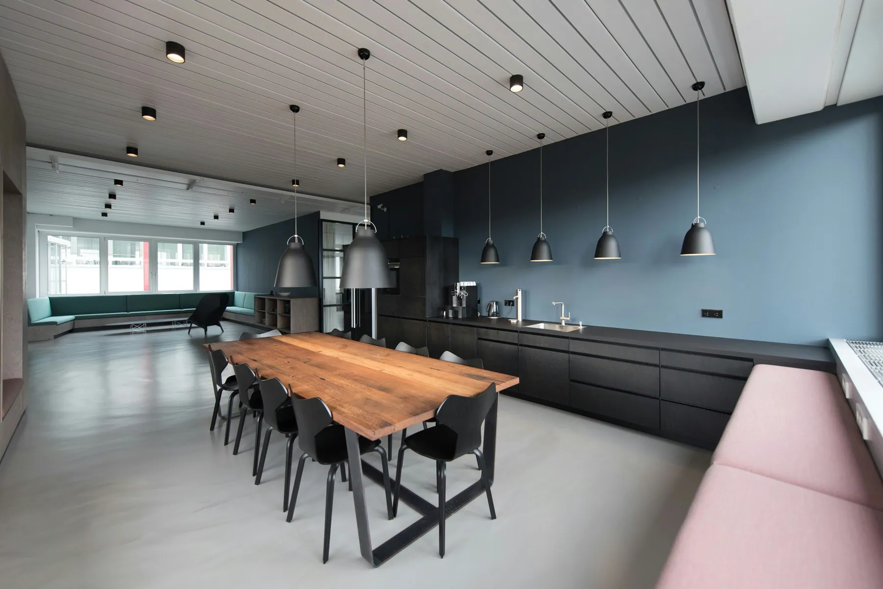 Office break room with a long wood table and pendant lights