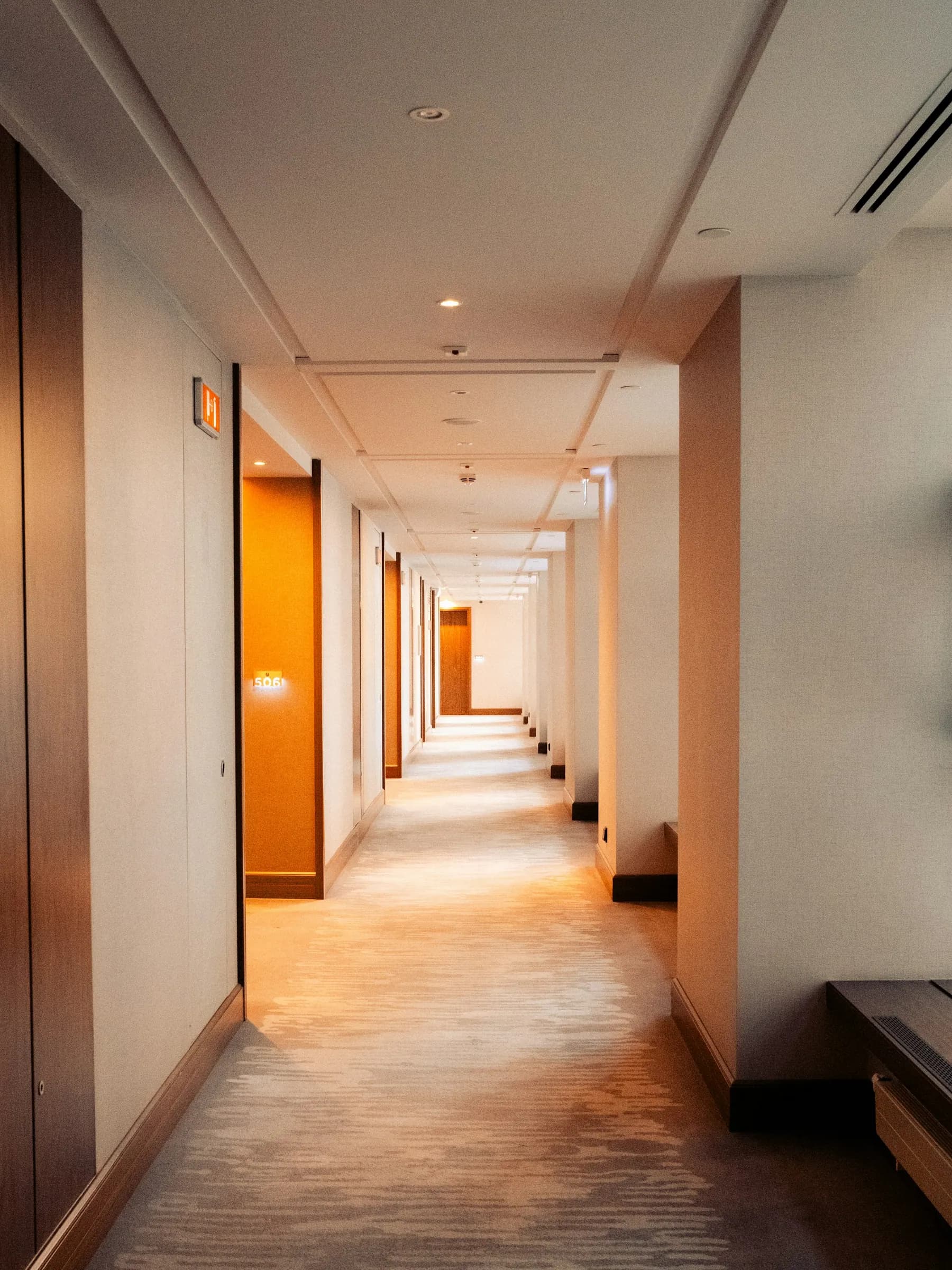 Long carpeted residential corridor with warm lighting
