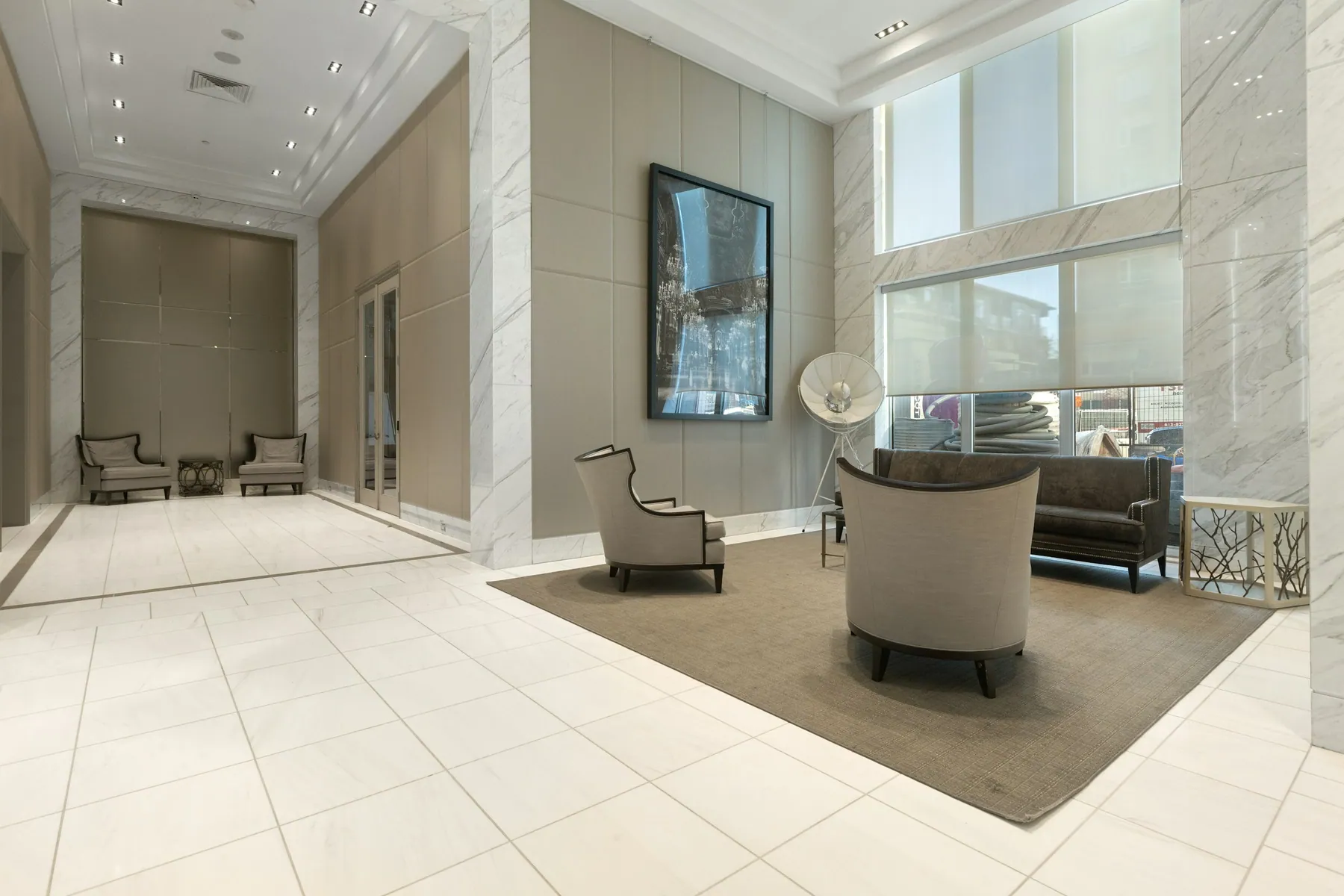 Double-height lobby with marble walls and lounge chairs