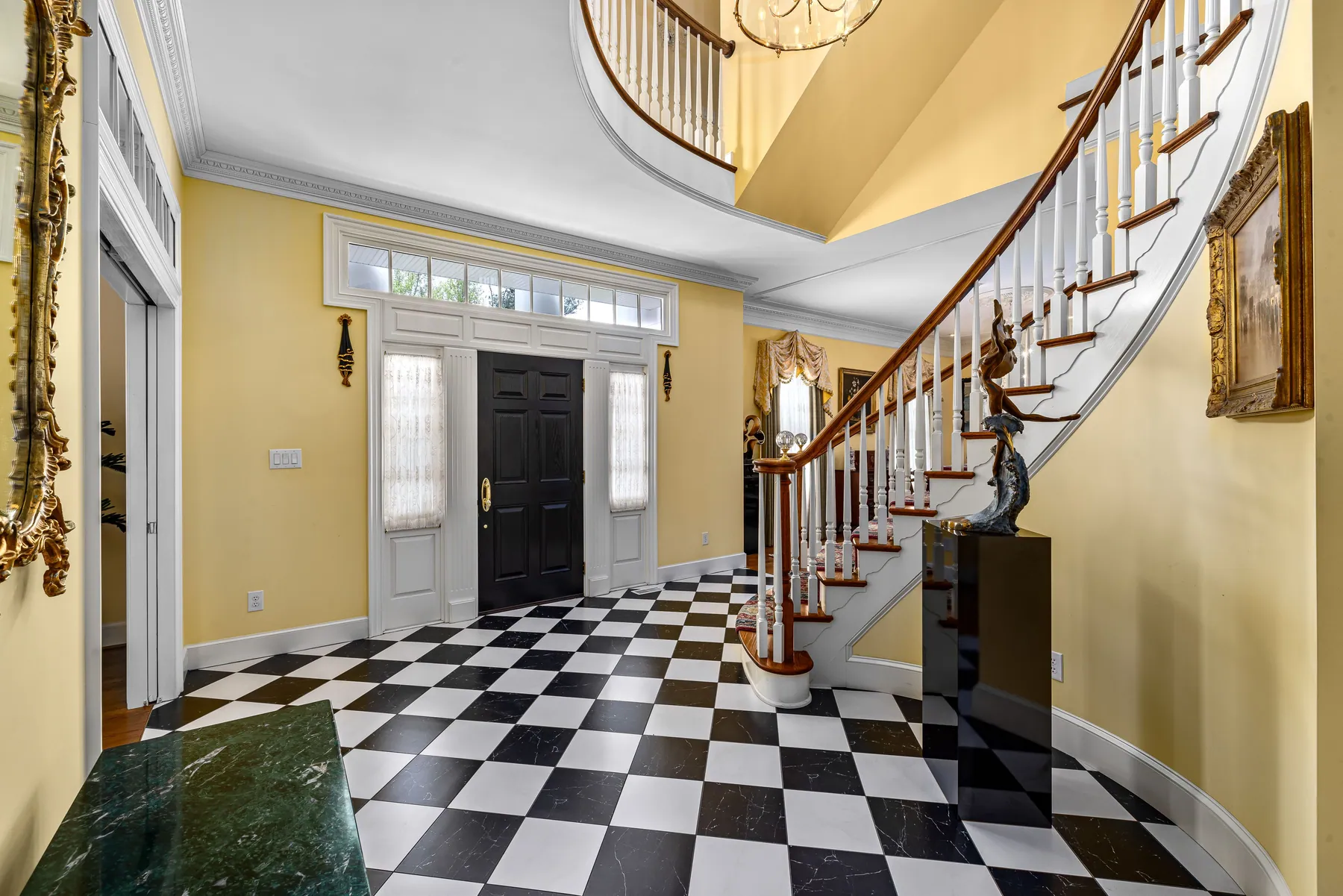 Formal foyer with a checkerboard marble floor and sweeping staircase