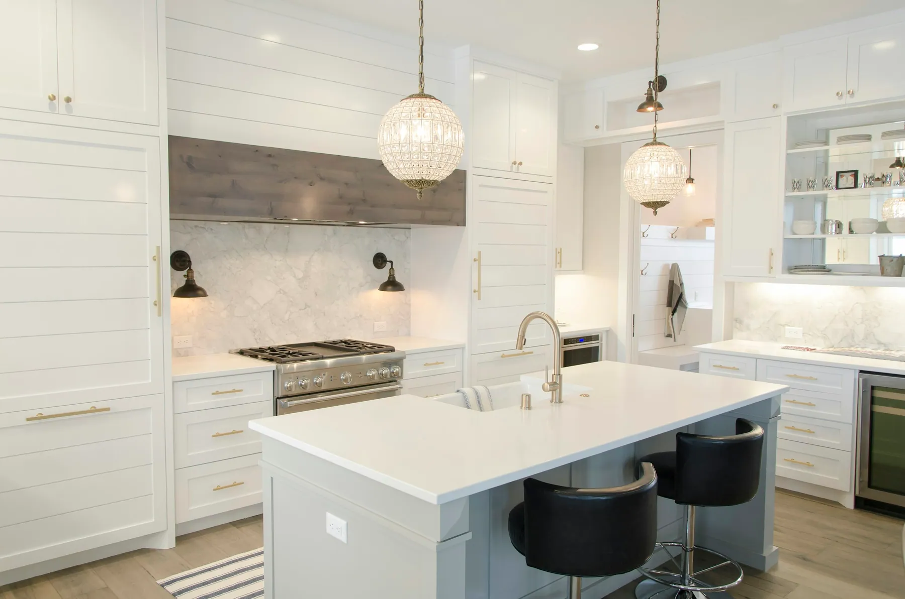 White shaker kitchen with an island, globe pendants and a range hood