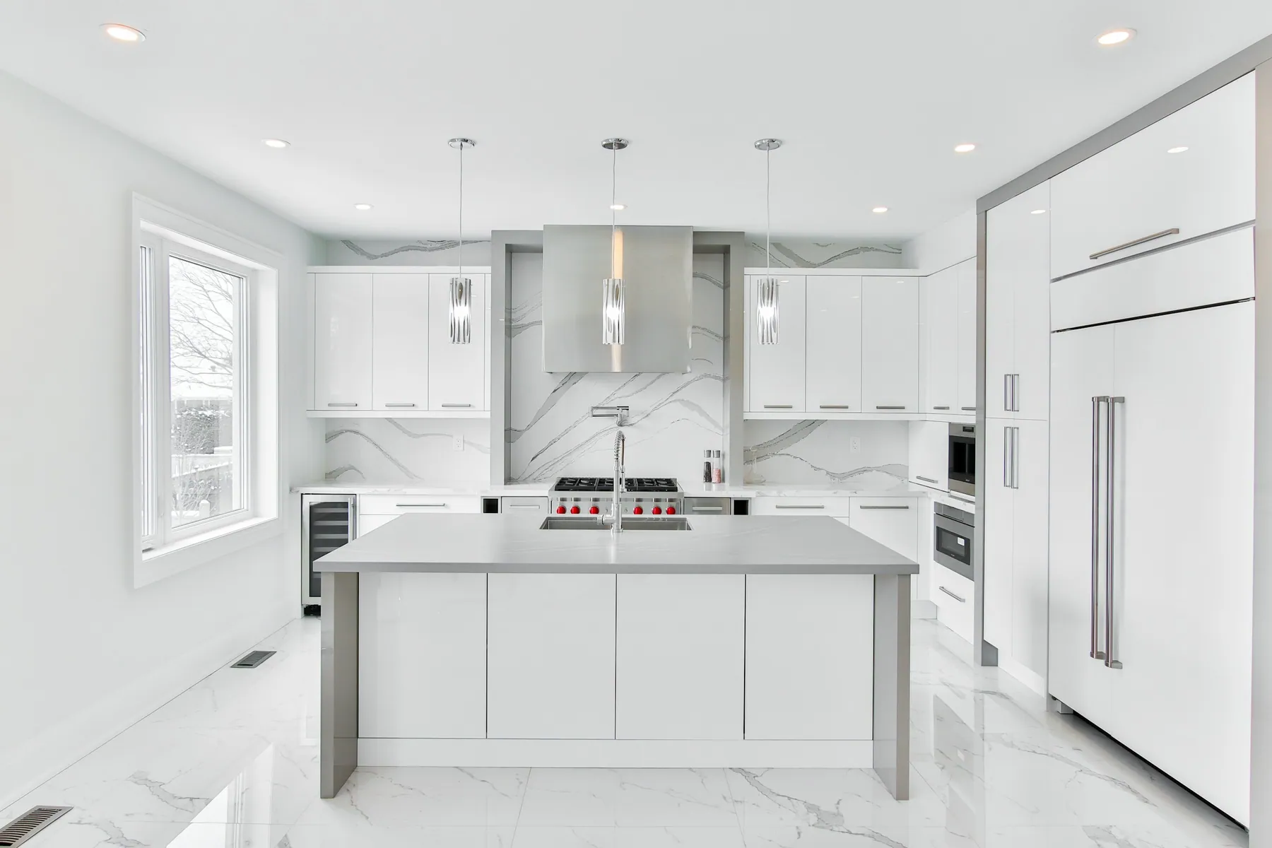 Sleek white kitchen with a marble backsplash and a gray island