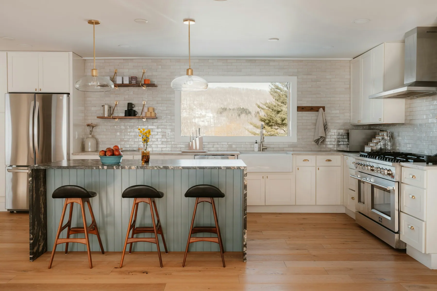 Kitchen with a sage beadboard island, three stools and a picture window