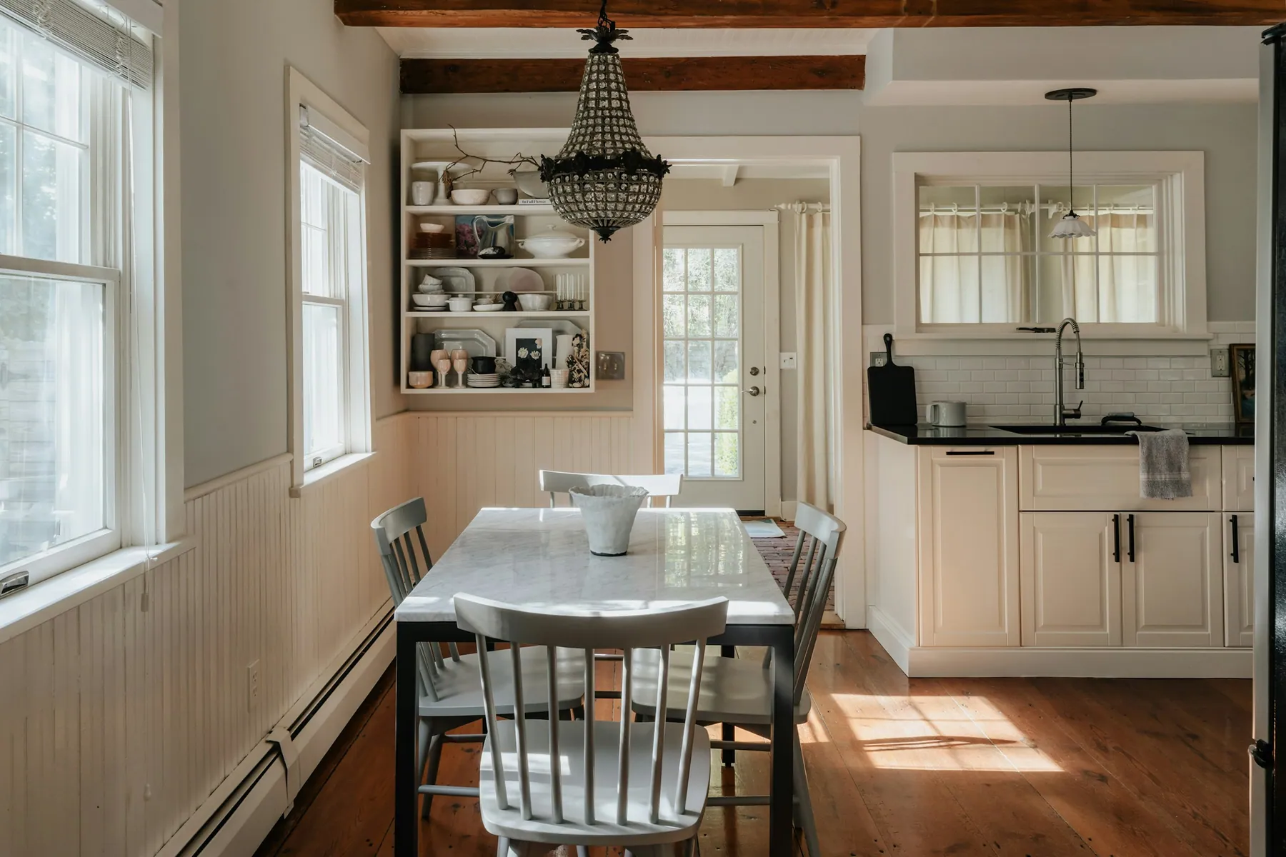 Farmhouse eat-in kitchen with wainscoting, open shelves and a chandelier
