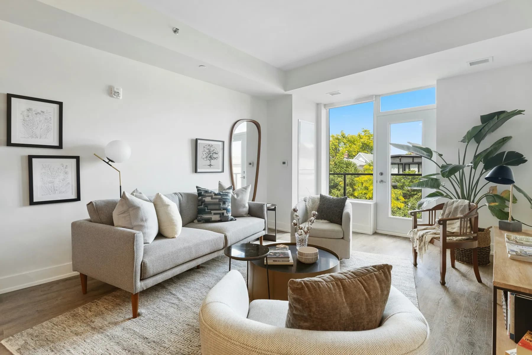 Bright living room with a gray sofa, plants and a balcony door
