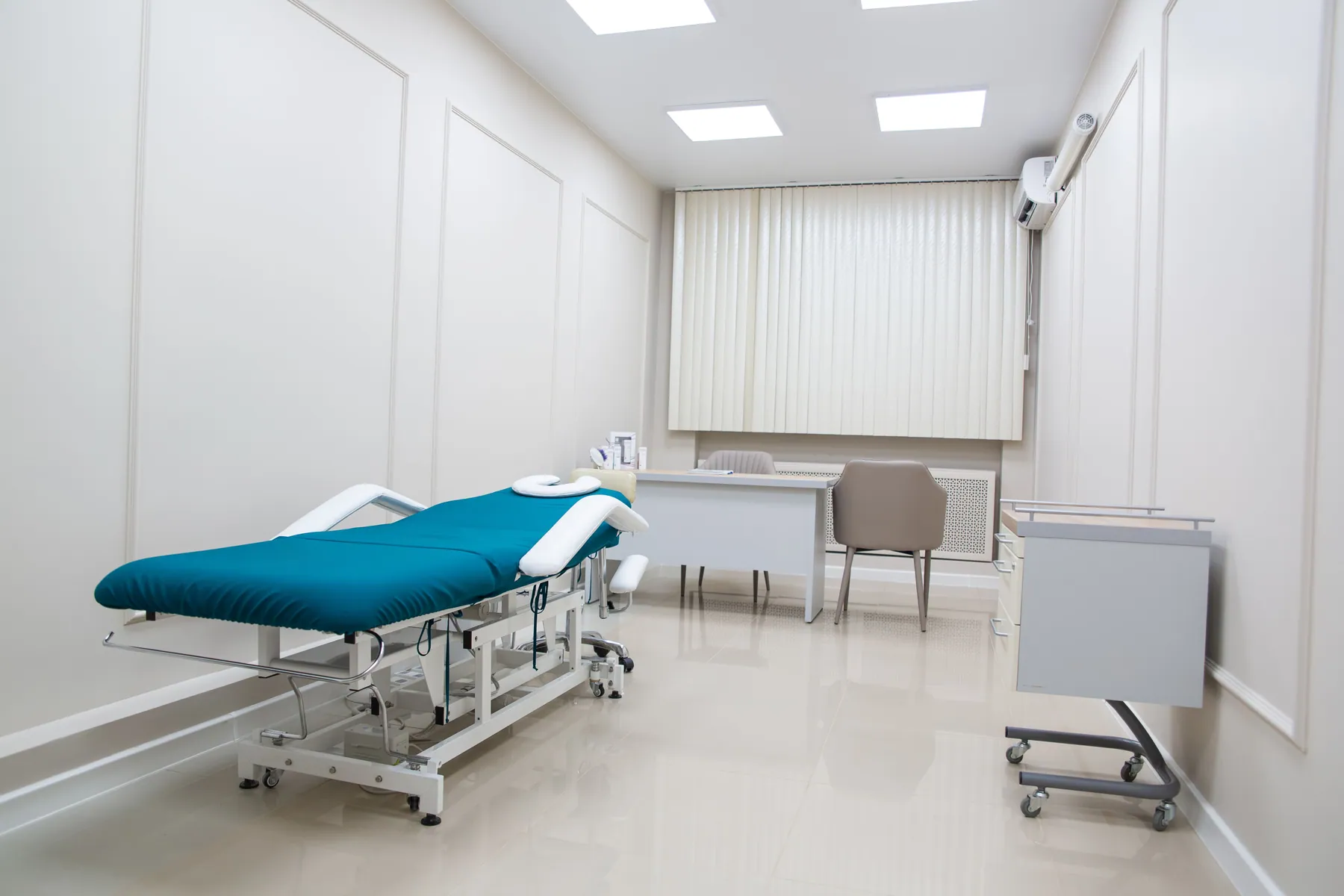 Treatment room with an adjustable exam table and desk