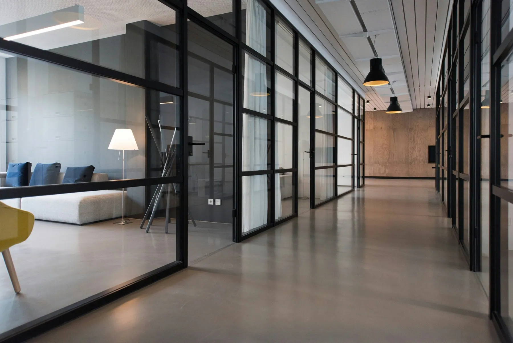 Office corridor lined with glass-walled meeting rooms
