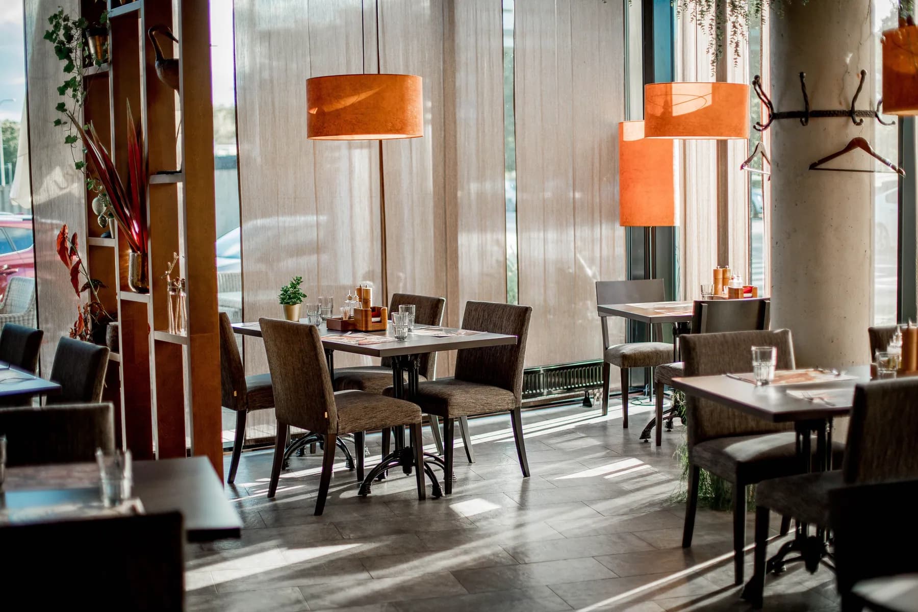 Sunny restaurant with orange pendant lights and wood tables